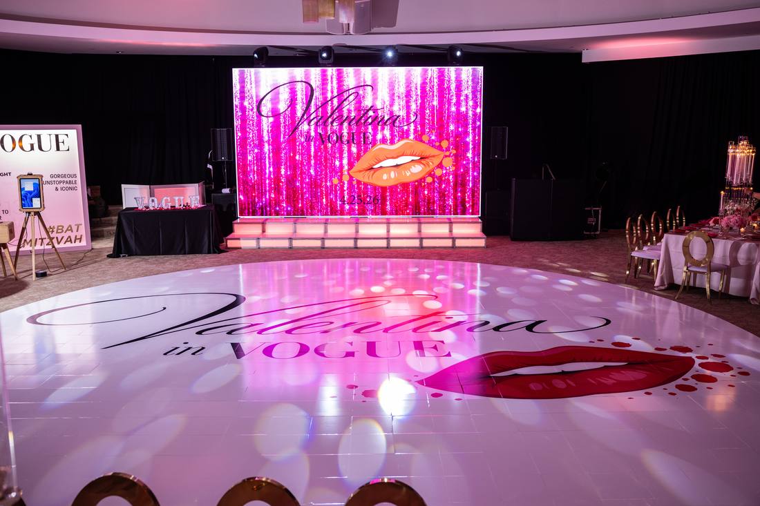 Illuminated dance floor with a personalized bat mitzvah logo and stage backdrop