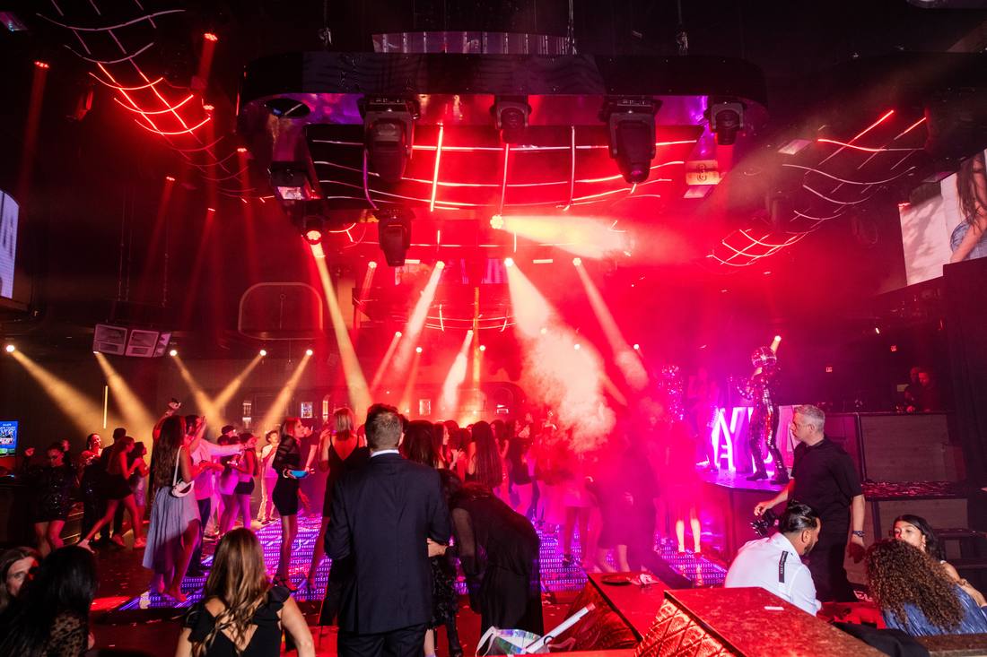Wide view of the dance floor under red lighting beams and haze