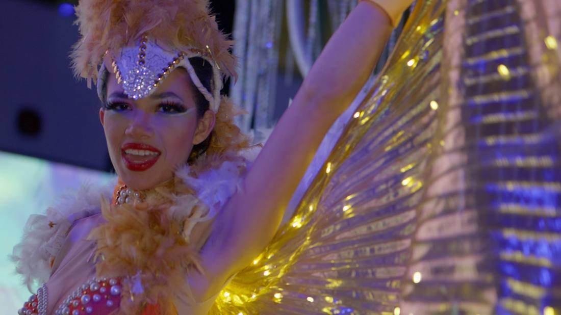 Dancer in a feathered headdress wearing an illuminated gold wing costume