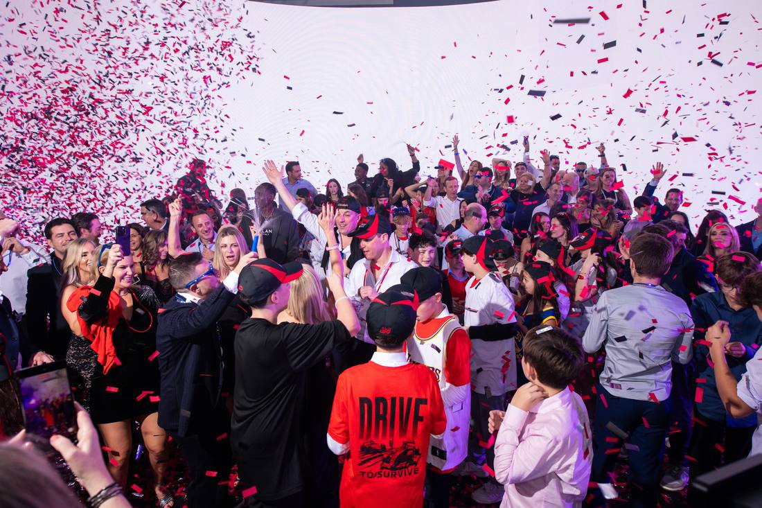Crowd cheering on the dance floor under a shower of red and black confetti