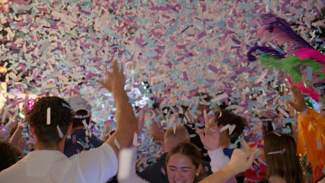 Guests reaching up through a burst of falling confetti and streamers