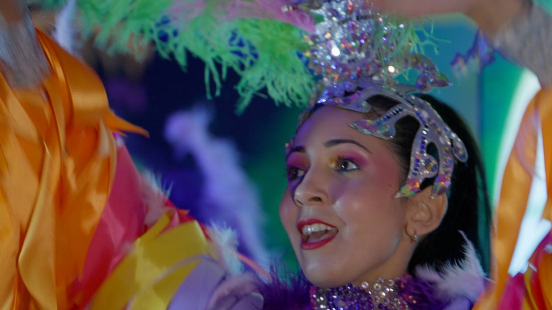 Close-up of a costumed performer in a feathered and jeweled headpiece