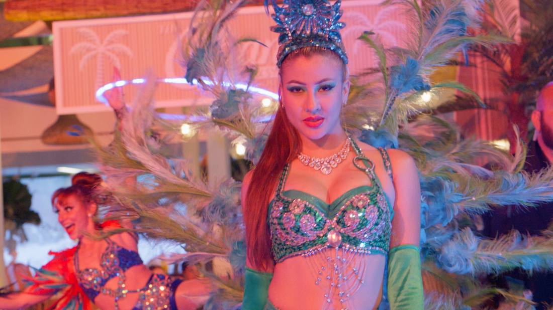 Costumed dancer in a jeweled green and pink carnival-style outfit