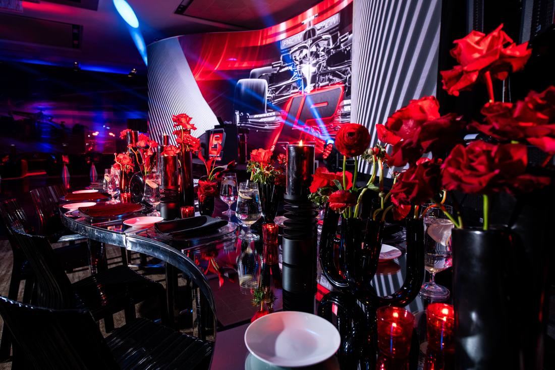 Motorsport-themed reception table with red roses and a racing video backdrop