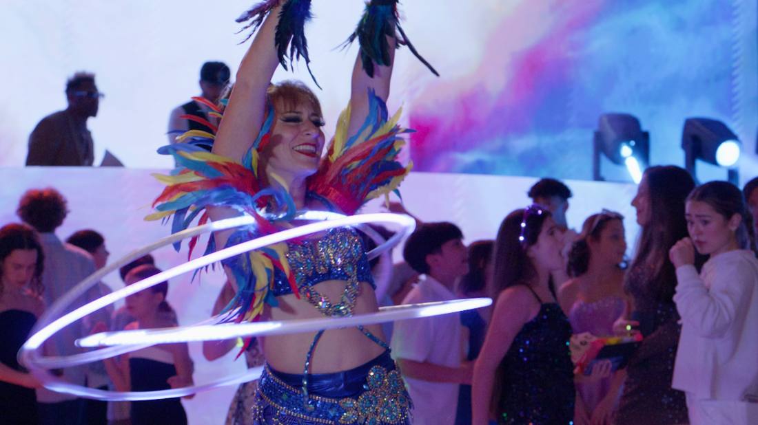 Performer in a feathered costume spinning illuminated LED hoops