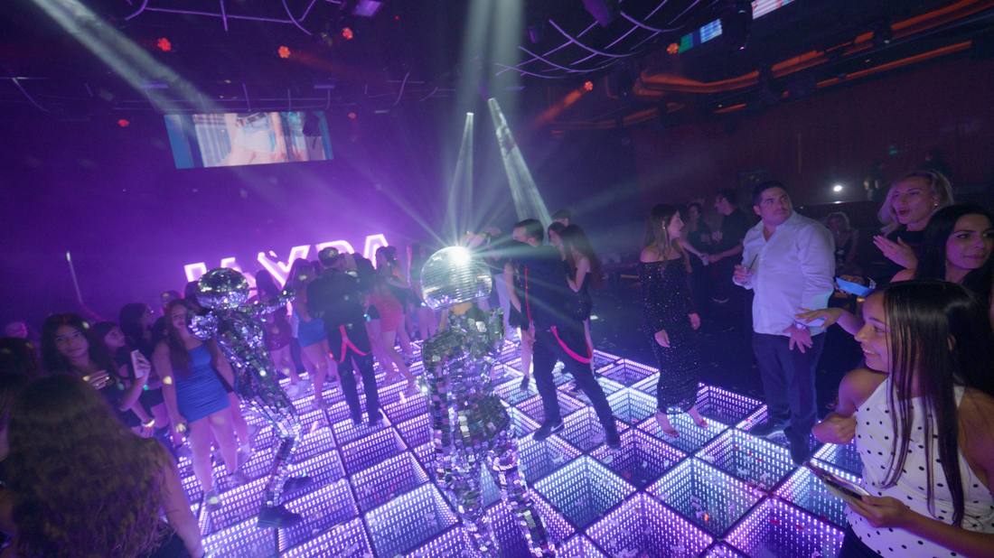 Mirrored disco-ball performers dancing on an illuminated dance floor