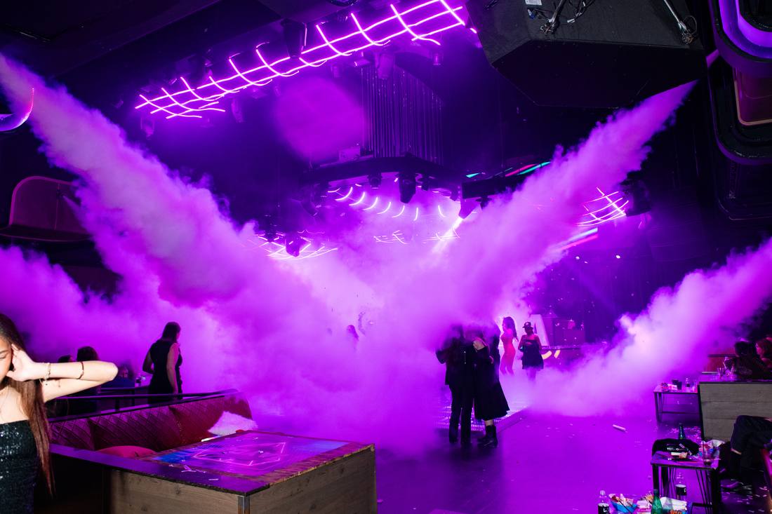 Purple fog rising over the dance floor as guests gather below