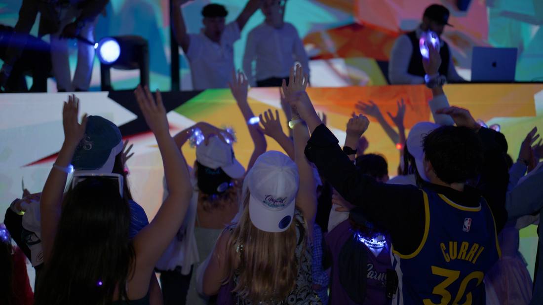 Guests with glowing wristbands dancing toward the DJ booth
