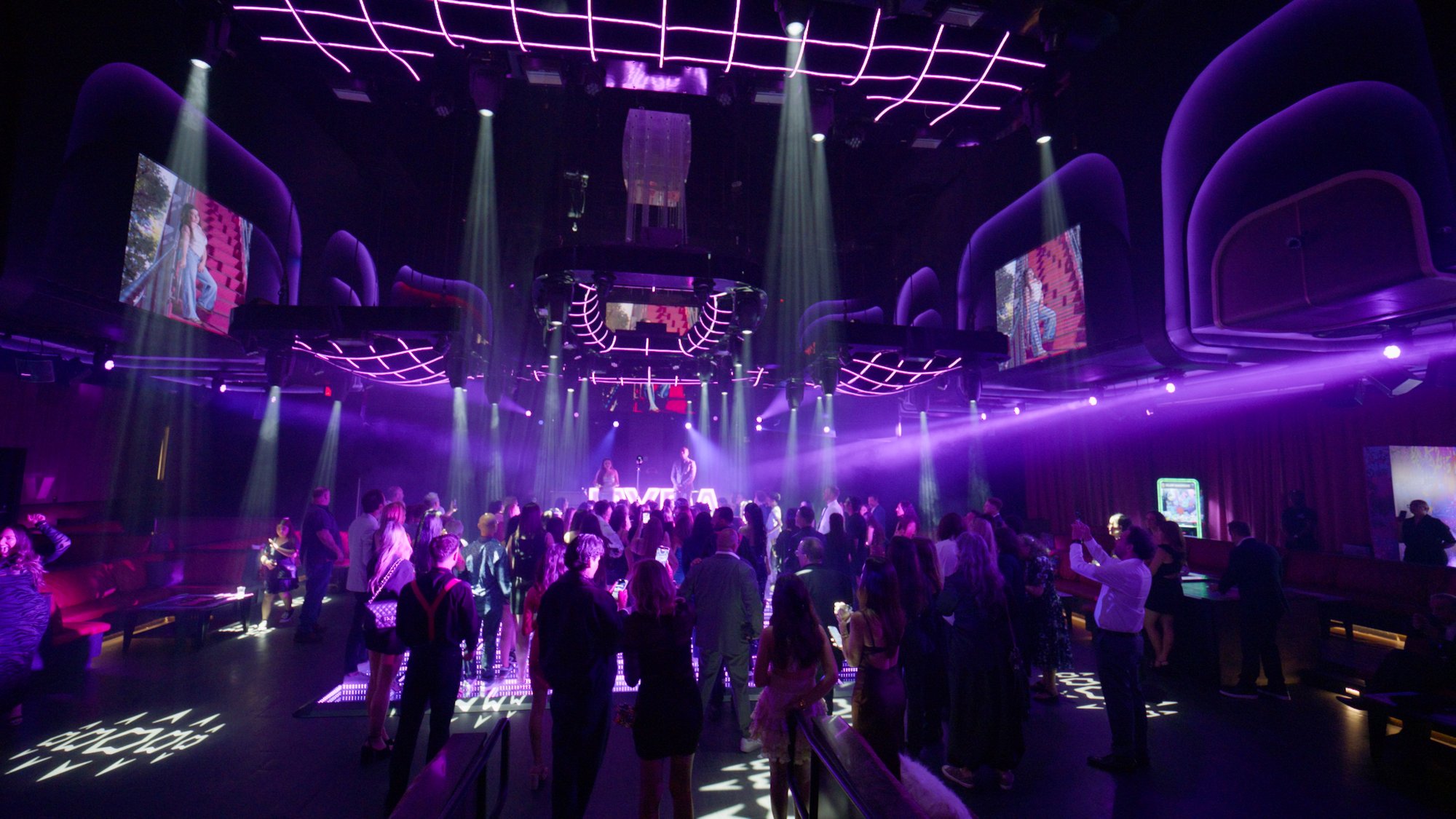 Packed nightclub dance floor under deep purple lighting